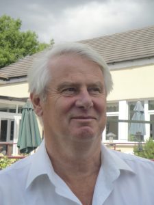 Man with grey hair in an open neck shirt