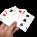 Four playing cards of different suits, all threes