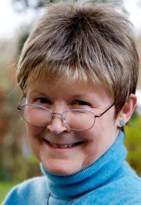 Smiling woman in blue polo neck and glasses