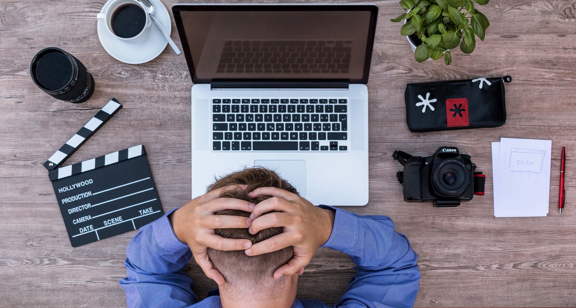 writing Man holding head in hands in front of keyboard